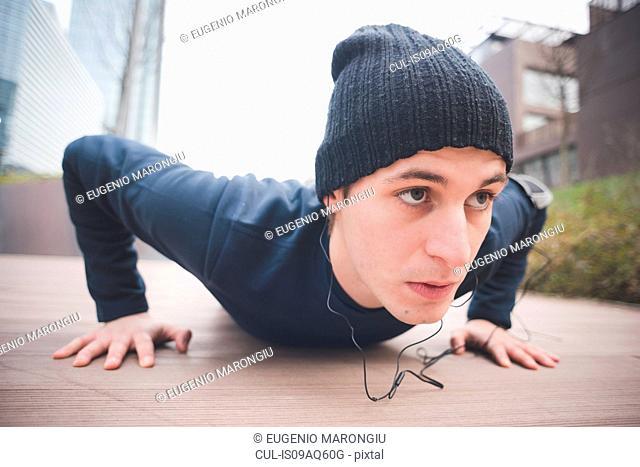 Close up of young male runner doing push ups in city