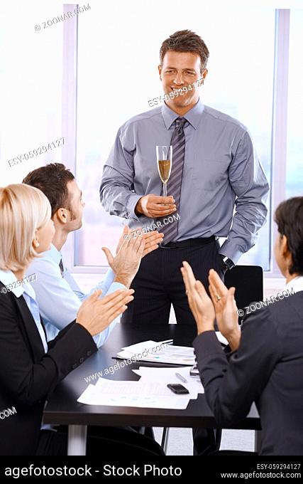Businesspeople clapping hands, celebrating success of businessman holding glass of champagne
