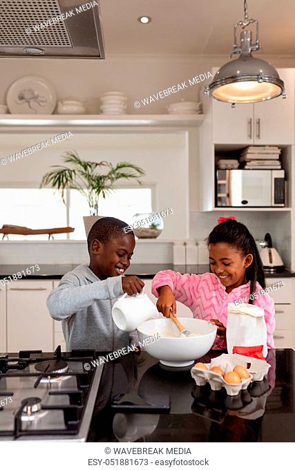Siblings preparing food on a worktop in kitchen at home