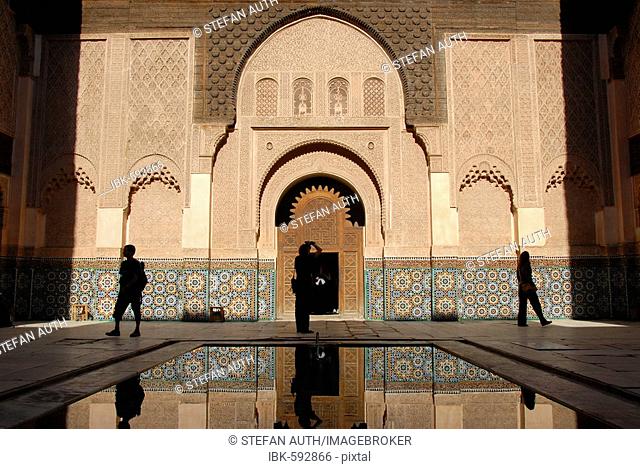 Human silhouettes in oriental designed harmonic yard with water pond Medersa Ali Ben Youssef medina Marrakech Morocco