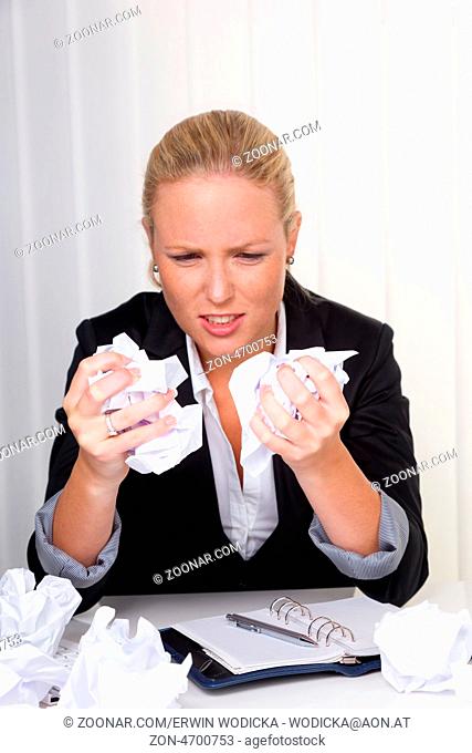 Eine Frau im Büro mit Papierknäuel. Ärger, Stress und Frust am Arbeitsplatz