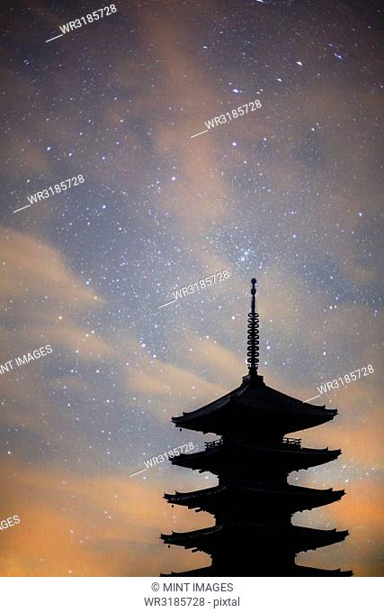 Silhouette of tall wooden pagoda of Buddhist temple against evening sky