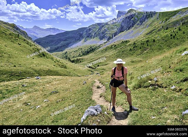 Hiker woman in a mountains and grasslands landscape. Valles Occidentales Natural Park. Hecho valley. Pyrenees mountain Range, Huesca, Aragon, Spain, Europe