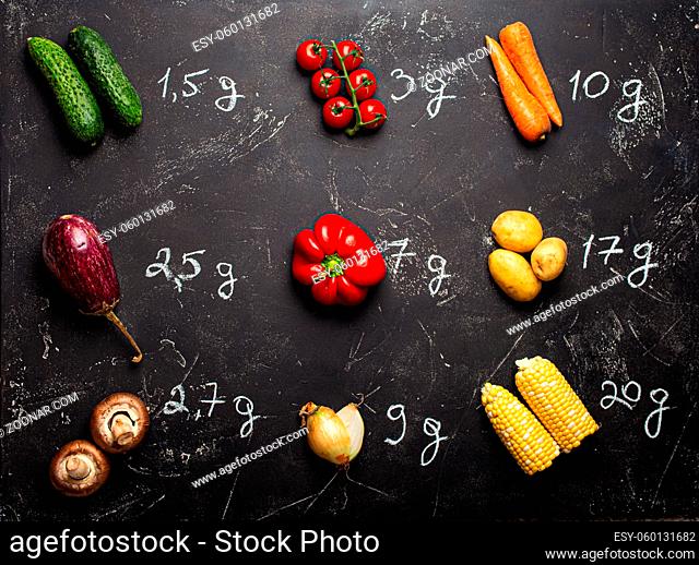 How many carbohydrates in different vegetables chart, fresh veggies with chalk wrote carbohydrates quantity on black stone background top view