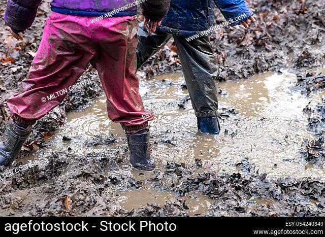 Young children playing in a muddy puddle