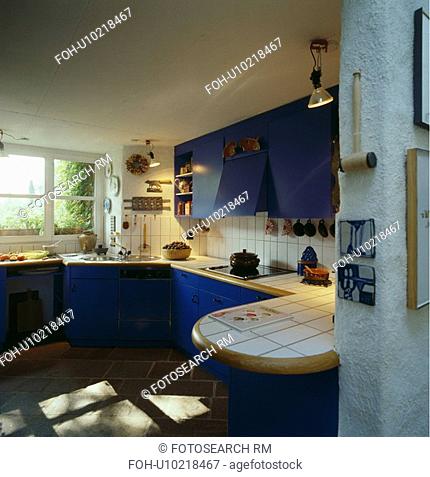 White tiled worktops and splashbacks in white kitchen with bright blue fitted cupboards