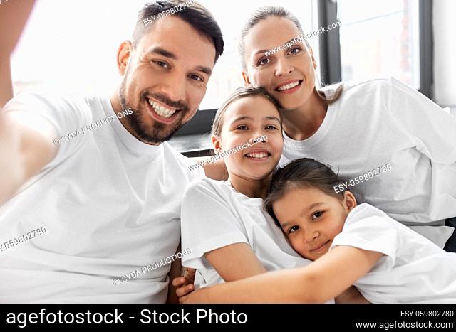 happy family taking selfie in bed at home