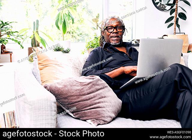 Businessman sitting on sofa with laptop at home
