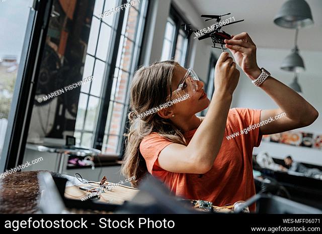 Teenage girl assembling miniature helicopter at home
