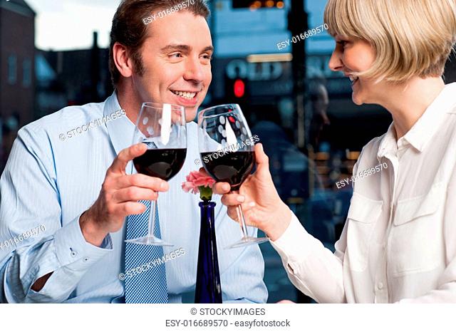 Attractive couple raises a glass of red wine in cafe