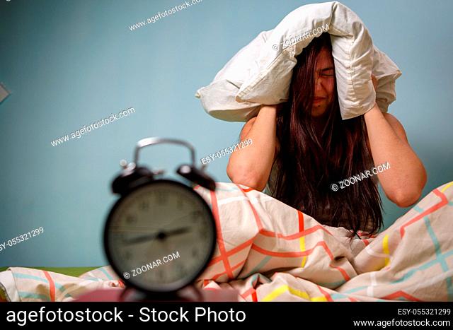 Woman with a pillow over her head, has trouble sleeping. Insomnia concept