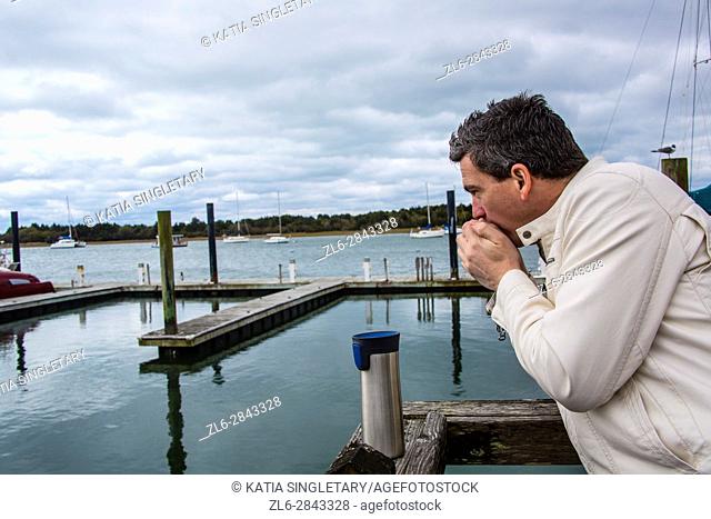 Caucasian handsome man in his 40's warming up drinking his hot beverage by the sea