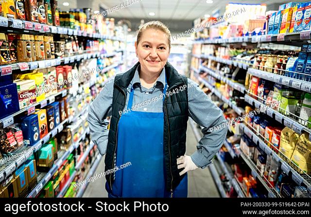 26 March 2020, Berlin: Ariane John, supermarket employee at Edeka in Berlin-Friedenau, looks into the photographer's camera