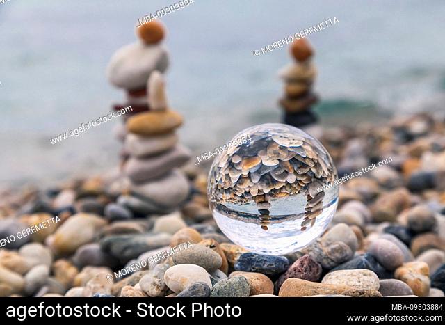 Stack of pebbles reflected in a crystal ball, Baska beach, island of Krk, Kvarner Bay, Primorje-Gorski Kotar County, Croatia