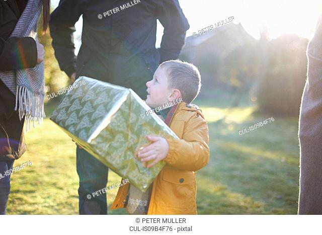 Happy boy carrying present with family in garden