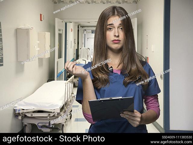 Overworked nurse holding clipboard in hospital hallway