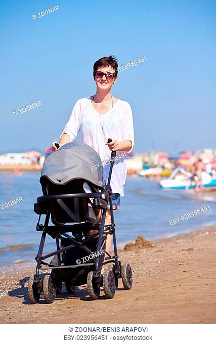 mother walking on beach and push baby carriage