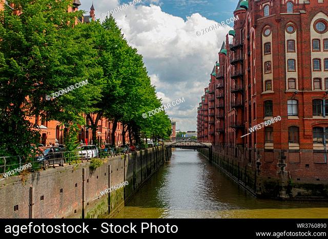 HAMBURG, GERMANY - JULY 18, 2015: a canal of Historic Speicherstadt houses and bridges at evening with amaising skyview over warehouses