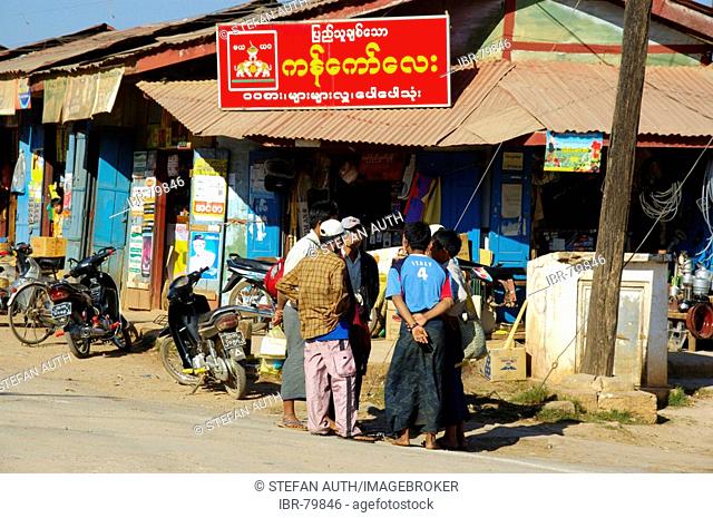 Group of men standing at a shop with sign in Burmese script Pindaya Shan State Burma