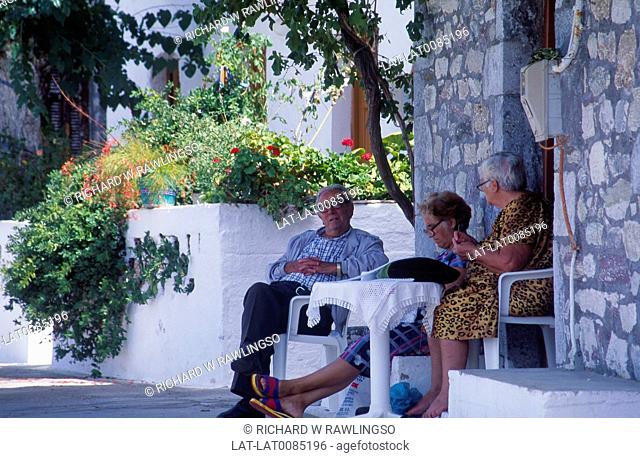 The Mani. Village on coast. House steps. Three mature people seated in shade