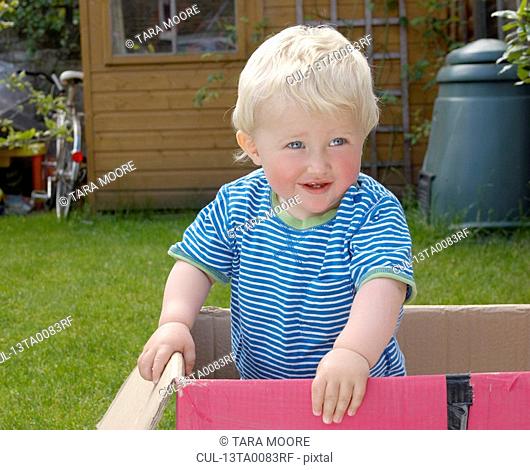 young boy standing in cardboard box