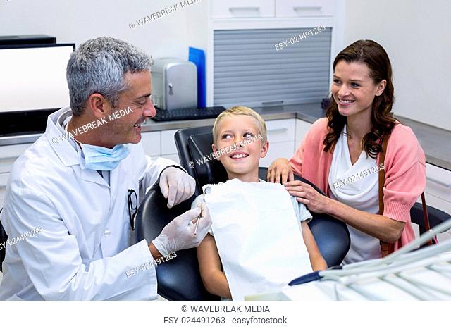 Dentist interacting with mother and son while dental examination