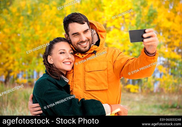 couple taking selfie with smartphone in autumn