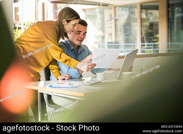 Businesswoman and businessman with laptop and documents at desk in office