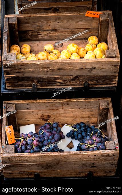 In the photo two old wooden boxes with inside the fruit (grapes and plums)