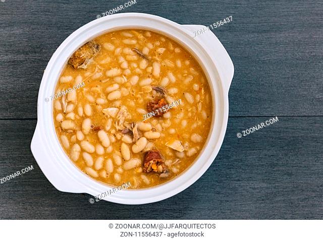 Spanish Fabada in white plate on rustic background with space for copy