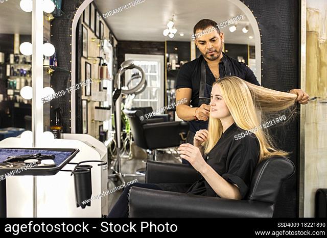 Stylist consults with young woman before hair appointment at boutique salon