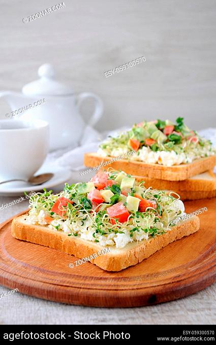 Sandwich for breakfast from tender, juicy germinated alfalfa sprouts with soft ricotta, tomato and avocado slices, with a cup of coffee or tea