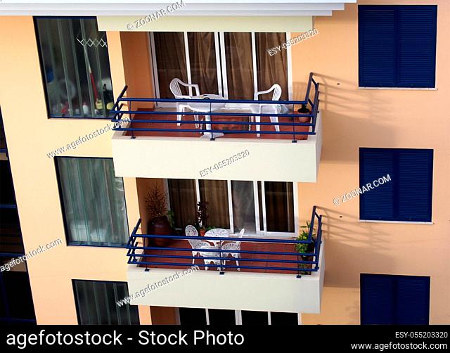 a row of balconies with tables and chairs in an orange and blue concrete apartment building