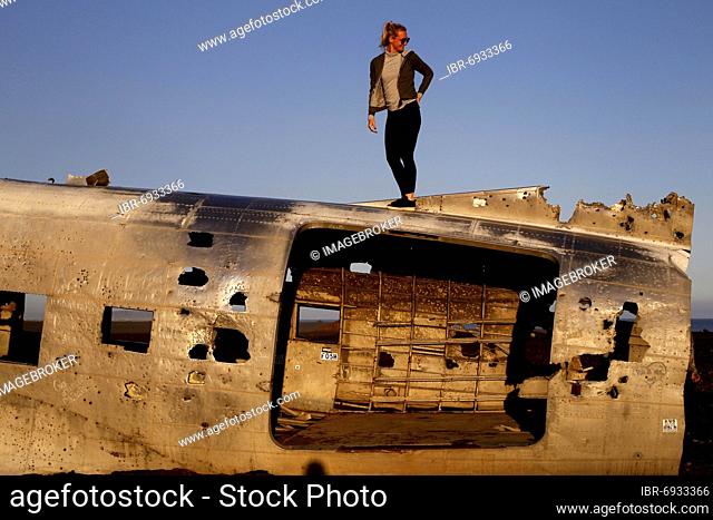 Woman climbing on plane wreckage, US Navy Douglas DC-3, Sander, Sólheimasandur, south coast, Iceland, Europe
