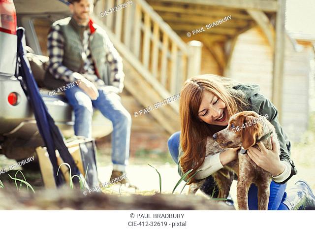 Woman petting dog outside cabin