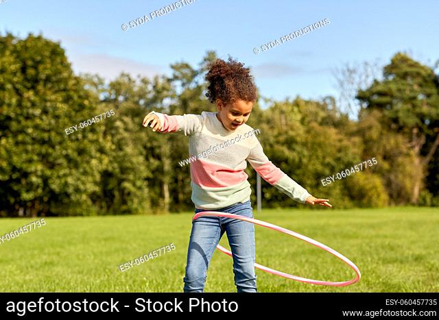 happy girl playing with hula hoop at park
