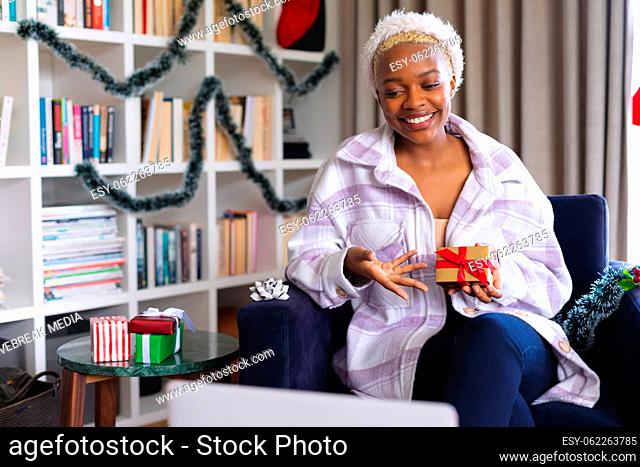 Happy african american woman wearing santa claus hat, using laptop for video call