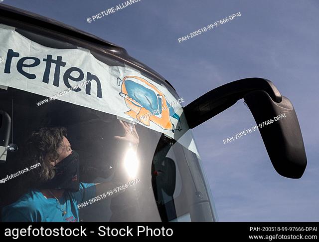 18 May 2020, North Rhine-Westphalia, Castrop-Rauxel: Bus operator Verena Suden from Dorsten wears a mouth-and-nose protection attached to a poster with the...