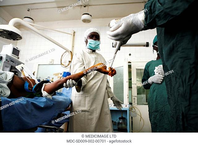 A surgeon swabs the skin of a patient's hand with antiseptic solution, reducing the risk of wound infection