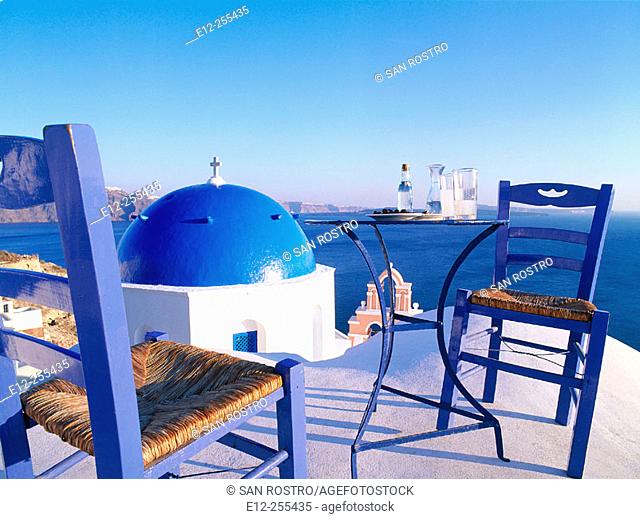 Greece, Cyclades Islands, Santorini, Oia village. Blue dome church. Ouzo & olives at sunset
