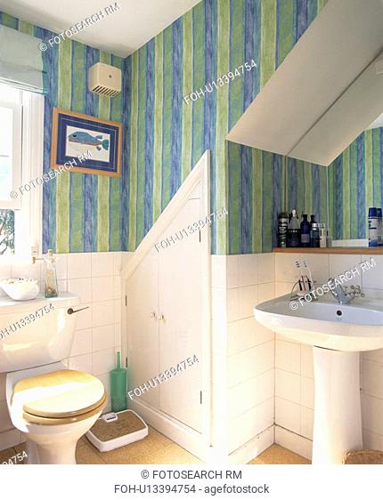 Scales beside toilet in small attic bathroom with pedestal basin and green+blue striped wallpaper