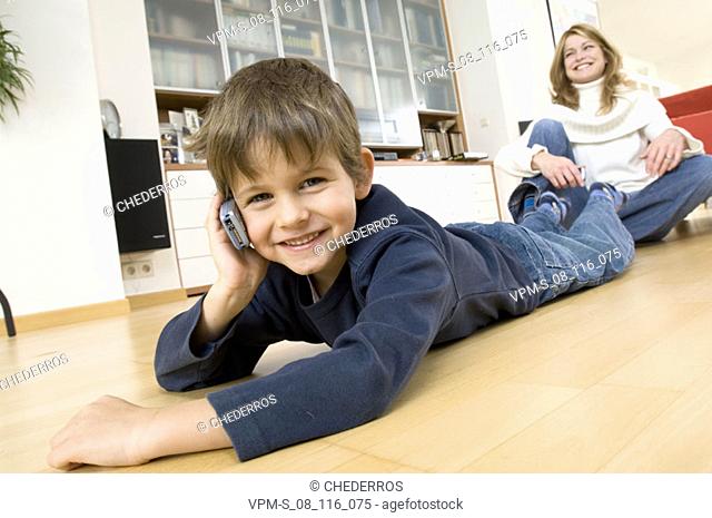 Portrait of a son using a mobile phone with his mother sitting behind him