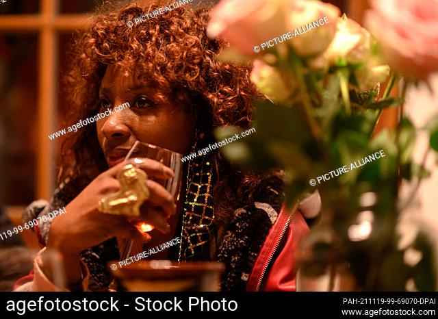 19 November 2021, Saxony, Dresden: A woman is sitting in a Spanish restaurant in the Baroque Quarter in the evening, holding a glass of wine in her hand