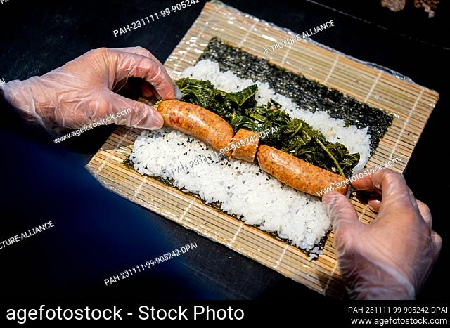 PRODUCTION - 07 November 2023, Lower Saxony, Oldenburg: A chef prepares sushi with kale and Pinkel in the kitchen of the Moto Kitchen restaurant
