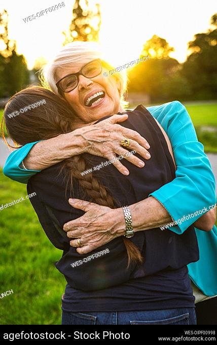 Grandmother smiling while embracing granddaughter in park