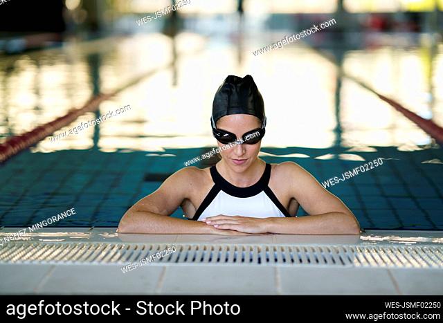 Female athlete wearing goggles at edge of pool in health club