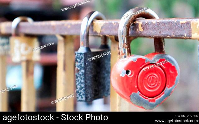 Shabby red lock in the shape of a heart. Valentine's day love concept. A padlock hanging on a metal railing is a sign of eternal love