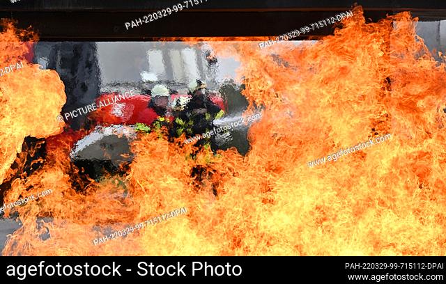 29 March 2022, Thuringia, Erfurt: Firefighters extinguish flames at a fire simulator at Erfurt-Weimar Airport, the air shimmers because of the heat