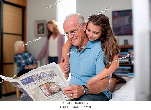 Girl hugging grandfather at home