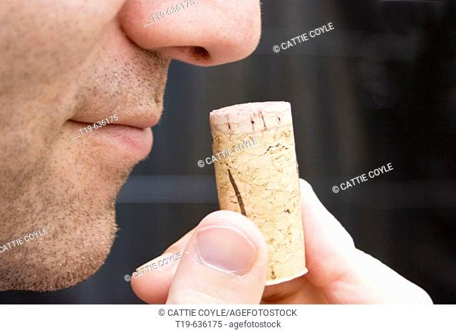 Man smelling the cork from a bottle of red wine